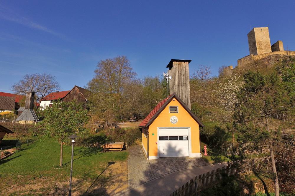 Feuerwehrhaus mit Burgruine im Hintergrund